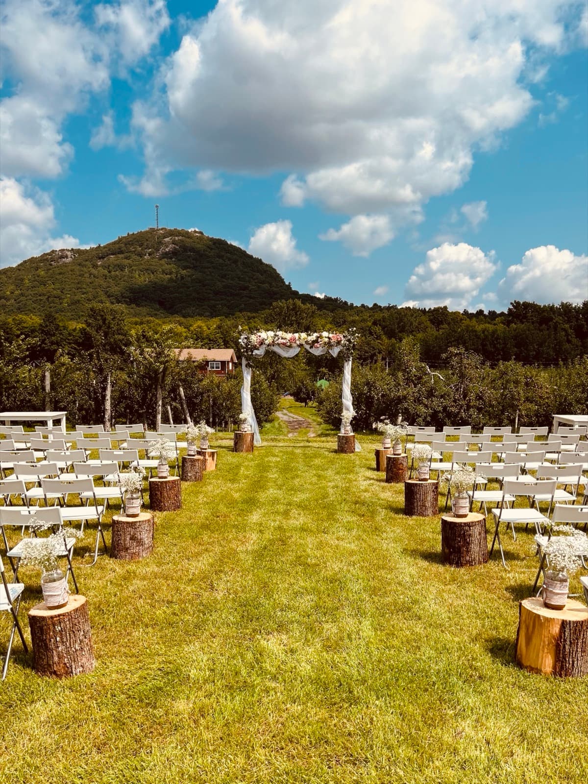Ceremony aisle with chairs and a floral arch facing Mont-Saint-Grégoire
