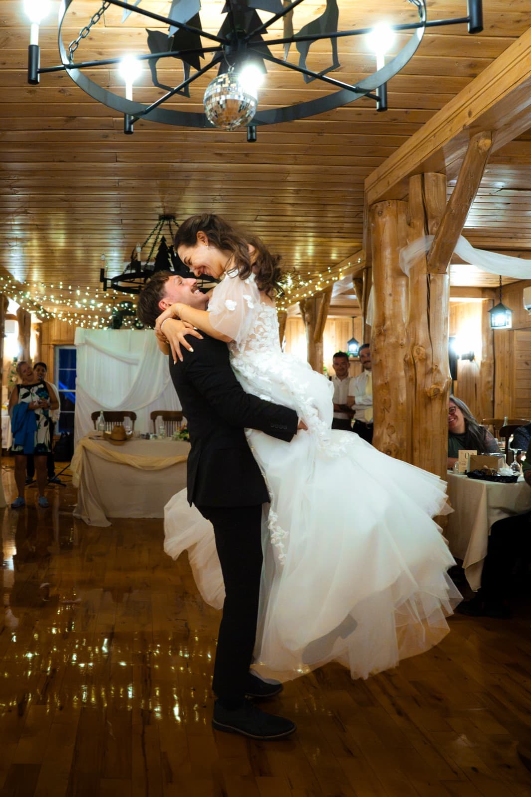 Newlyweds' first dance in the wooden hall, string lights and disco ball