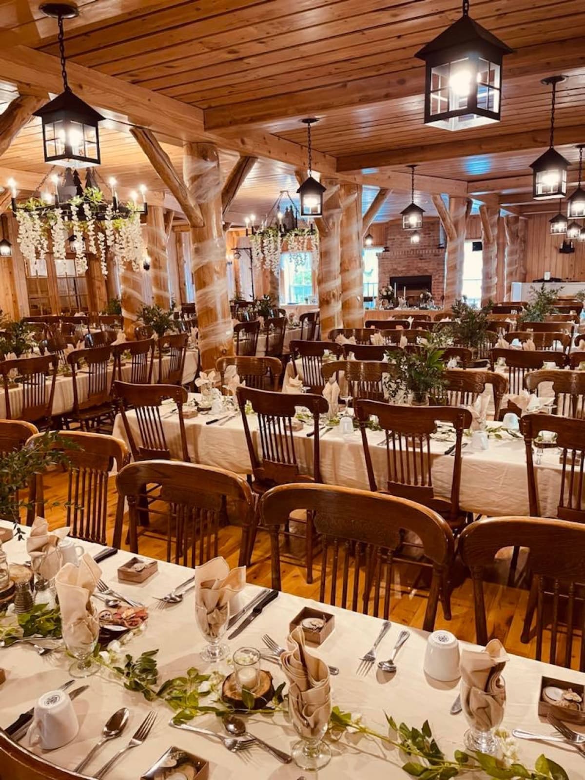Salle de réception dressée, tables en bois, guirlandes et lanternes